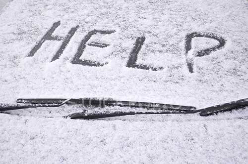 Snow covered car windscreen with the word help written in the snow