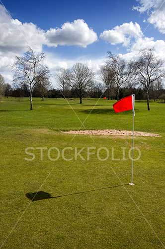 Red flag and bunker on the green of a gold course